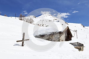 Chalet and wooden cross in deep snow