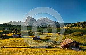 Chalets at Seiser Alm with Langkofel mountain in background at sunrise, Dolomites, South Tyrol, Italy