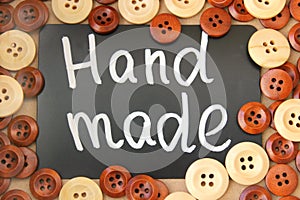 Chalk Board with the inscription `handmade` surrounded by brown and white wooden buttons