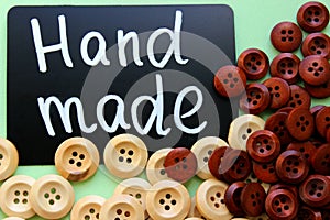 Chalk Board with the inscription `handmade` surrounded by brown and white wooden buttons