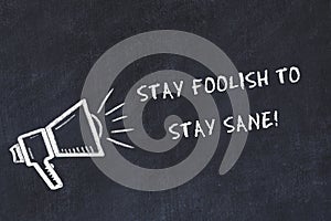 Chalk board sketch with loudspeaker and motivational phrase stay foolish to stay sane photo