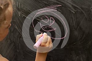 Chalk in a child`s hand. Children`s hand on the background of the chalk board. The child writes, draws.