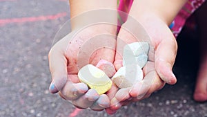 Chalk in child`s hands close-up. The child drawing a chalk on asphalt. Child drawings paintings on asphalt concept.