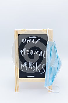 Chalk-described chalk board with note only medical masks with surgery mask in the foreground at Covid-19 times