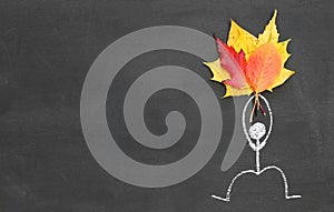 Chalk drawing icon man holding a bouquet of autumn leaves on blackboard or chalkboard background. autumn or seasonal concept. cop