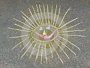 Chalk drawing of a smiling sun on asphalt