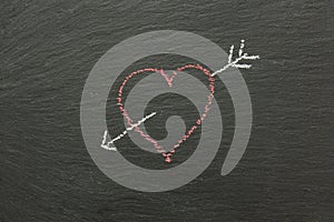 Chalk heart with arrow drawn on a chalk board.