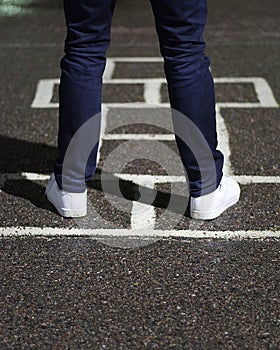 Chalk hopscotch game on asphalt with a person ready to play