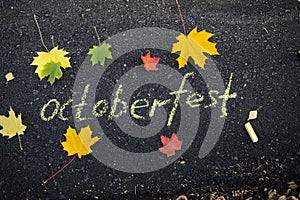 Chalk inscription on the asphalt Oktoberfest. Autumn leaves on the pavement