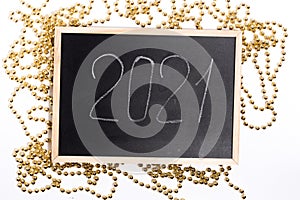 A chalk plaque with the inscription 2021, around the golden beads. New Year's Eve