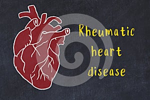 Chalk sketch of human heart on black desc and inscription Rheumatic heart disease