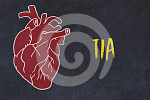 Chalk sketch of human heart on black desc and inscription TIA photo