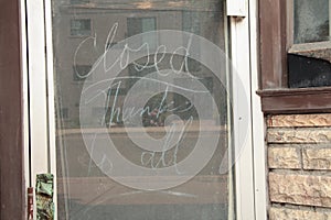 chalk writing closed thanks to all on chalkboard inside down window storefront. p