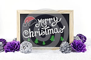 Chalkboard with Christmas decoration on snow white isolated background, and text `Merry Christmas` written on it