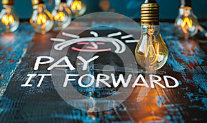 Chalkboard concept with lightbulbs and highlighted PAY IT FORWARD message, representing the idea of passing on a good deed and