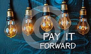 Chalkboard concept with lightbulbs and highlighted PAY IT FORWARD message, representing the idea of passing on a good deed and