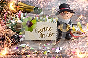 Chalkboard with four leaf clover and chimney sweeper and sparklers with bonne annee 2020 on wooden background