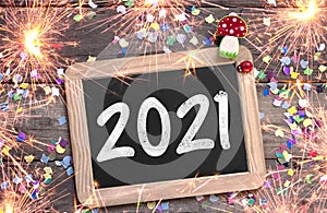 Chalkboard with four leaf clover and chimney sweeper and sparklers with happy new year 2021 on wooden background