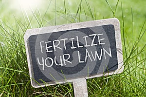 Chalkboard in the grass with fertilize your lawn