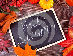 Chalkboard with Hello Autumn text. Composition with pumpkin, autumn leaves and red pears. Cozy autumn mood concept