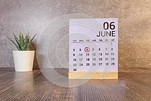 Chalkboard with June 04 calendar date on white cube block on wooden table.