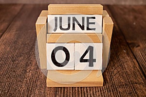 Chalkboard with June 04 calendar date on white cube block on wooden table