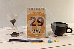 Chalkboard with May 29 calendar date on white cube block on wooden table