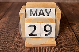 Chalkboard with May 29 calendar date on white cube block on wooden table