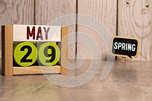 Chalkboard with May 29 calendar date on white cube block on wooden table