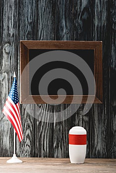 Chalkboard near funeral urn with ashes and american flag