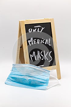 Chalkboard with note only medicals masks as warning with medical mask in the foreground at Covid-19 times