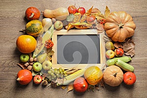 Chalkboard with space for text, autumn vegetables and fruits on wooden background. Happy Thanksgiving day