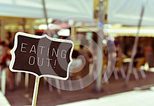 Chalkboard with the text eating out in the terrace of a restaura