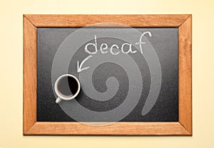 Chalkboard with word decaf and cup of coffee on beige background, top view