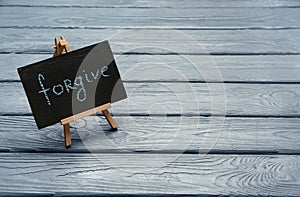 Chalkboard with word FORGIVE on wooden background