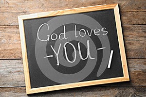 Chalkboard with words GOD LOVES YOU on wooden background