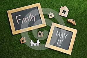 Chalkboards and wooden figures on green grass, flat lay. International Family Day