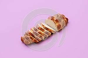 Challah bread isolated on purple background. Sliced braided bread