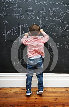 Challenge accepted. a young boy with a blackboard full of math equations.