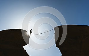 Challenge, risk, concentration and bravery concept. Silhouette a man balance walking on rope over precipice