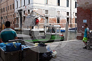 Men loading trash on garbage boat, Venice