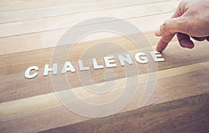 Challenge word with male hand on wood table.