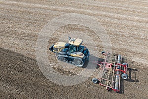 A Challenger MT 865 E tractor pulls the disc harrow through the field to prepare the soil