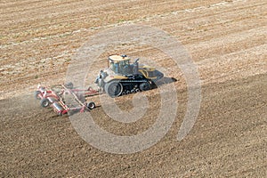 A Challenger MT 865 E tractor pulls the disc harrow through the field to prepare the soil