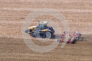 A Challenger MT 865 E tractor pulls the disc harrow through the field to prepare the soil