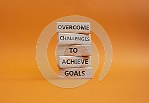 Challenges or goals symbol. Wooden blocks with words Overcome challenges to achieve goals. Beautiful orange background. Busine