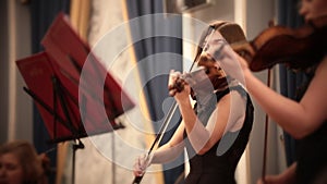 Chamber orchestra. A young woman playing violin during a musical performance.