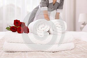 Chambermaid making bed in hotel, focus on fresh towels