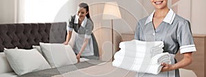Chambermaid with stack of fresh towels in hotel room, closeup view with space for text. Banner design