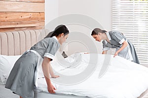 Chambermaids making bed in hotel room